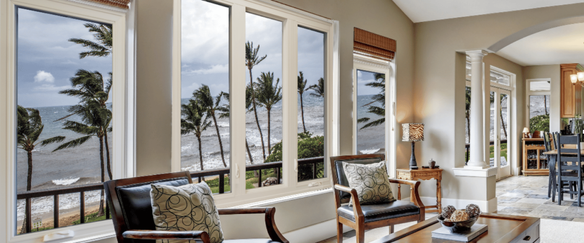 living room with impact windows looking out at a rough ocean